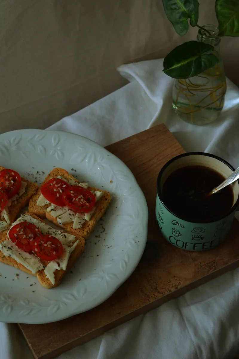 Tostada de tomate y queso fresco junto a una taza de café, un desayuno mediterráneo de diario
