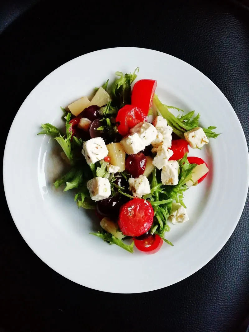 Ensalada de verduras variadas servida en un plato blanco sobre una mesa