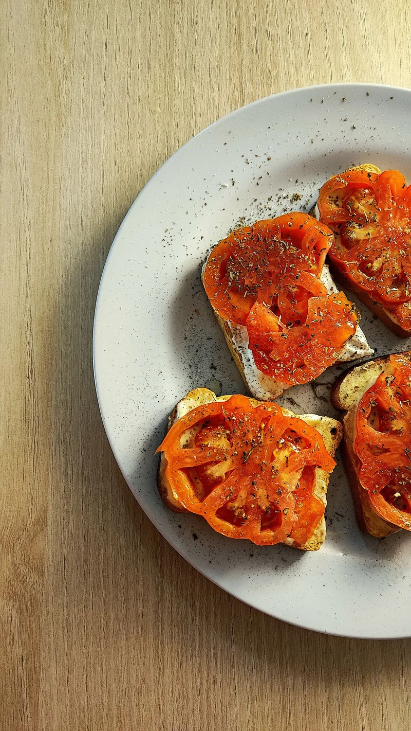 Rebanadas de pan con tomate fresco, albahaca y aceite de oliva sobre una tabla de madera
