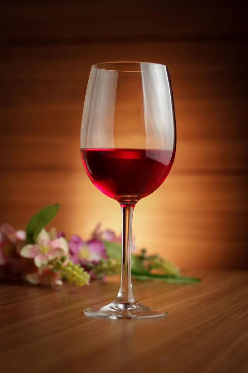 Copa de vino tinto servida sobre una mesa de madera